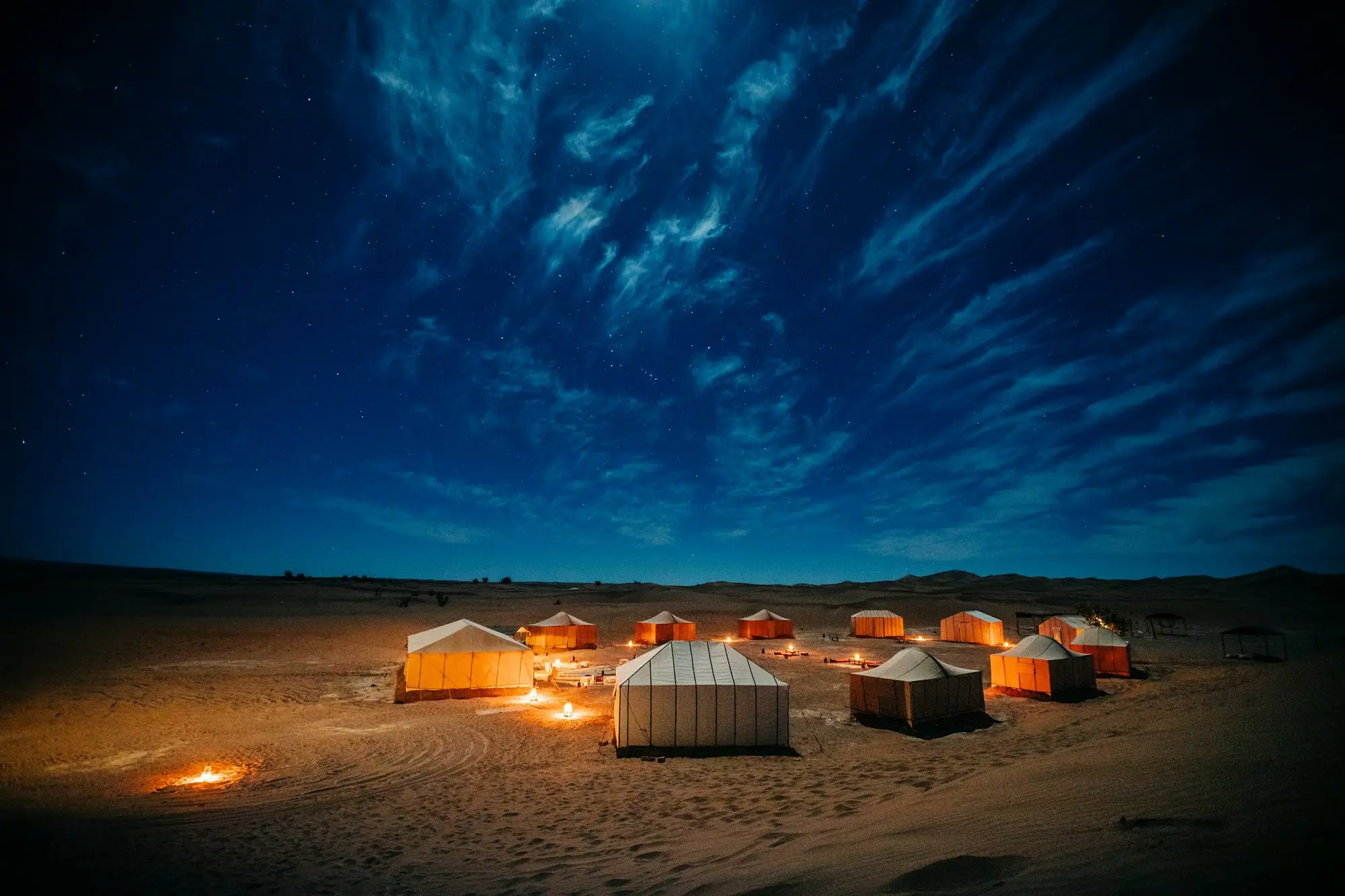 Les tentes d'un bivouac éclairées à la tombée de la nuit dans le désert de M'hamid