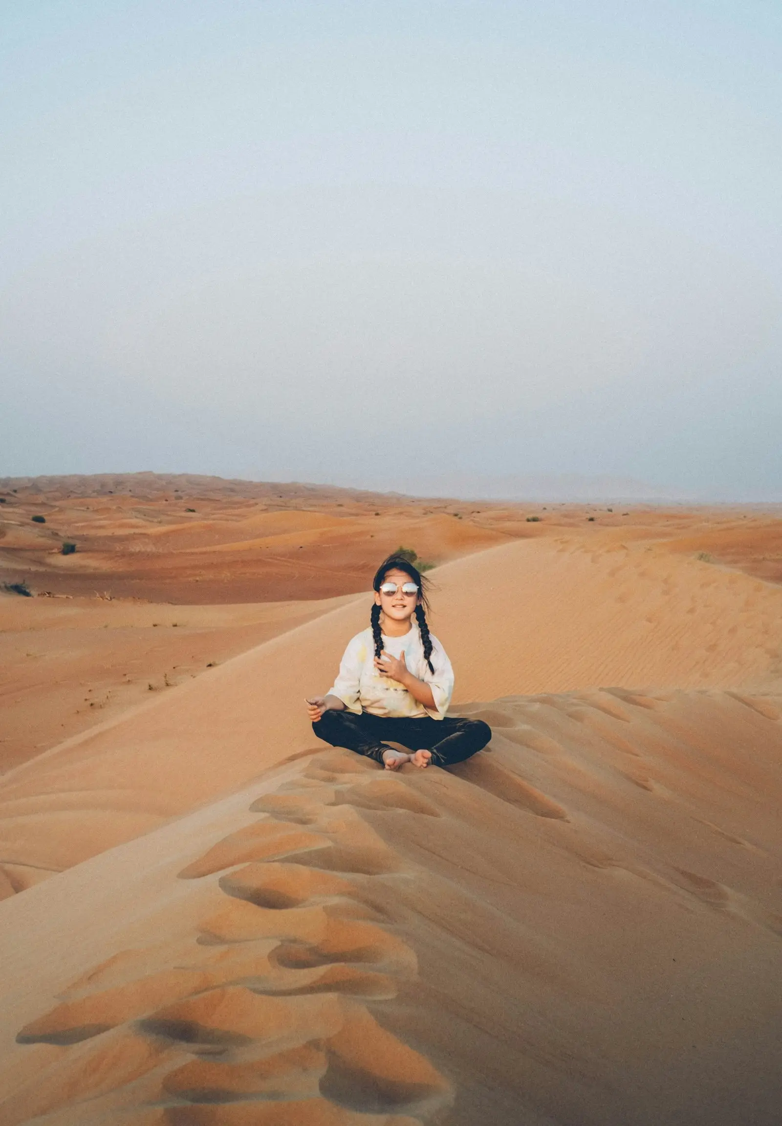 Une femme assise en tailleur au sommet d'une dune